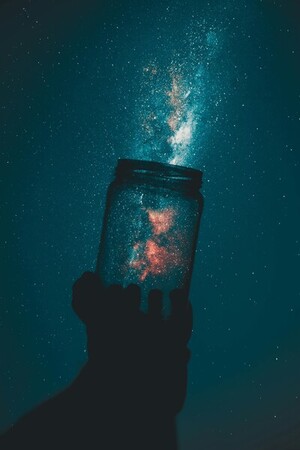 Person Holding Glass Mason Jar Under A Starry Sky